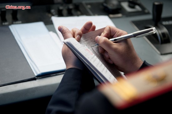 The locomotive's chief engineer and driver Ding Hailong writes in the log book. [Photo by Chen Boyuan / China.org.cn]