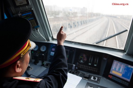 The train's chief engineer Ding Hailong uses hand gestures to confirm he has received Song Jian's notice for a railway signal ahead in the distance. [Photo by Chen Boyuan / China.org.cn]