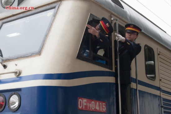 Song Jian (R) and his master, the locomotive's chief engineer jointly perform a visual confirmation of the singal ahead before the train departs from station. [Photo by Chen Boyuan / China.org.cn]