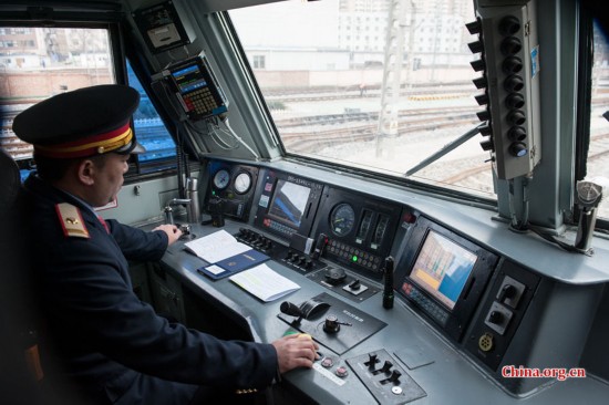 The locomotive's chief engineer and driver Ding Hailong checks all meters before setting the locomotive in motion. [Photo by Chen Boyuan / China.org.cn]