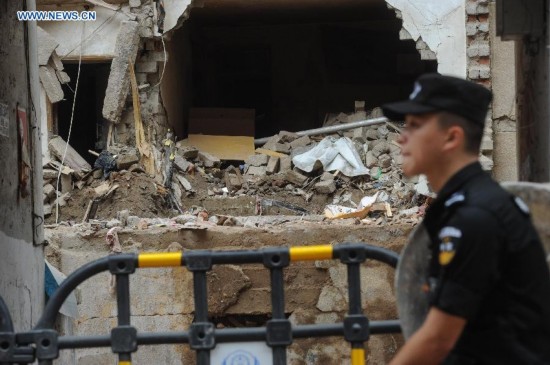 A policeman patrols at the site of building collapse in Zunyi, southwest China's Guizhou Province, June 15, 2015. 