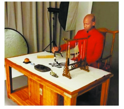 马布里穿唐装写毛笔字 用汉子写下家字(图)