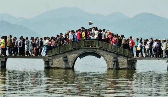 图为杭州西湖断桥游人如织。 如果在假期打算去家喻户晓的旅游名胜地观光的话,那么请你一定要做好挨挤的准备。每个黄金周,故宫、长城、西湖等大家耳熟能详的著名旅游景点,无一不是 人山人海。大家挤在一处,摩肩擦踵,寸步难移。在这种情况下,与其说看风景,还不如说是看人。