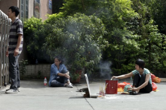 在广州市纺织服装职业学校门口,家属摆著死者的遗像,在烧香祭奠其