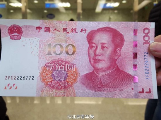 新版"土豪金"百元大钞拿到手 市民围观拍照