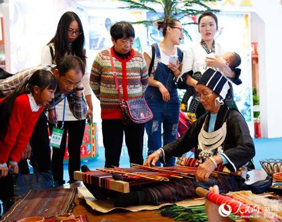 在海南展厅,以为老人在展示黎锦技艺。(人民网 李发兴 摄)