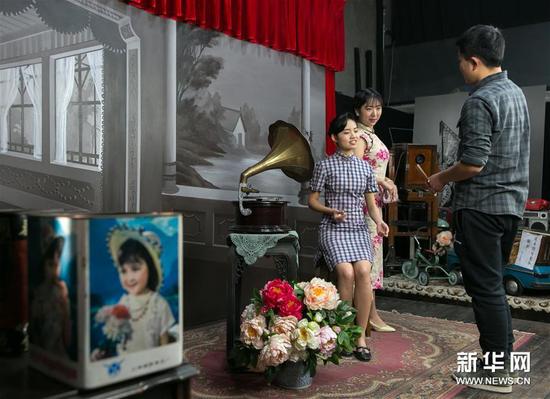 在白夜照相馆内,白夜照相馆的工作人员为顾客演示拿扇子的动作(1月10日摄)。