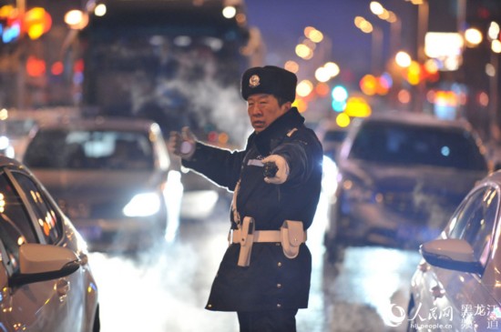 進入晚交通高峰，交警王敬華被霧霾和尾氣籠罩，在車流中執勤。楊志勇 攝 
