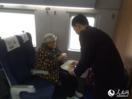 在除夕當天的列車上，列車員正在給82歲的老人遞水，她正要去蚌埠與家人團聚過年。（人民網記者 劉茸 攝影）