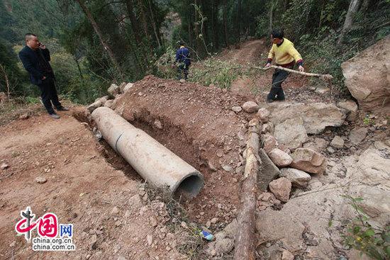 村民正在处理被挖断的道路之二——涵管暴露,并在路上植树,用树枝