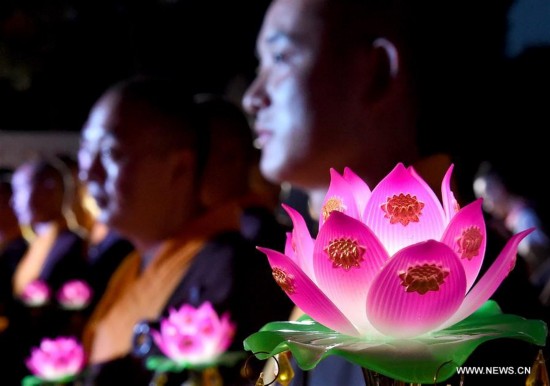 Monks carrying lotus-pattern lamps attend a buddhist ritual at the Shaolin Temple on the Songshan Mountain in Dengfeng City, central China's Henan Province, Aug. 13, 2016.