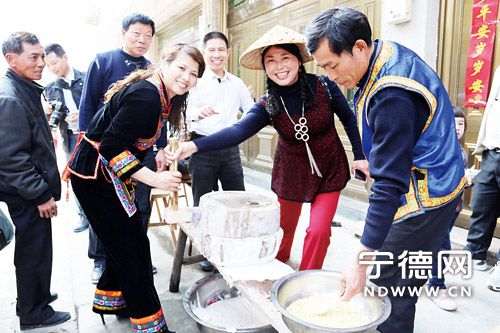 身着华丽畲族服饰的畲家女热情邀请“二月二”嘉宾一同磨豆浆做豆腐。
