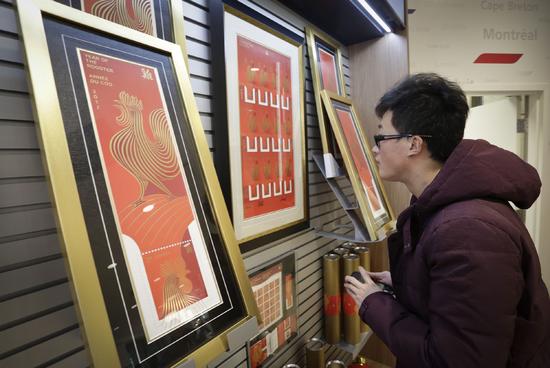 一名男子在一家郵局欣賞中國雞年生肖郵票相關紀念品