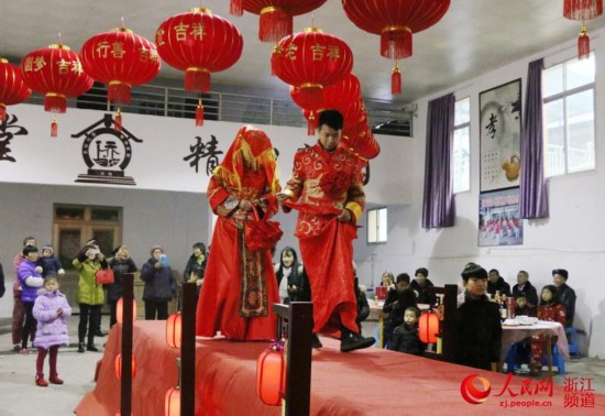 新郎牵着新娘走上喜台。他们身后,是“文化礼堂 精神家园”几个大字。