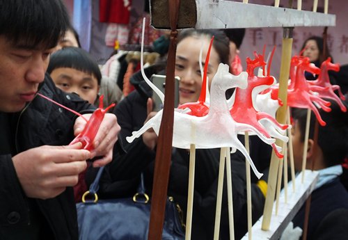 Two workers hang a giant lantern for a temple fair. Inset: A <em>tangren</em> (blown candy) master creates candy figurines. Photos: IC