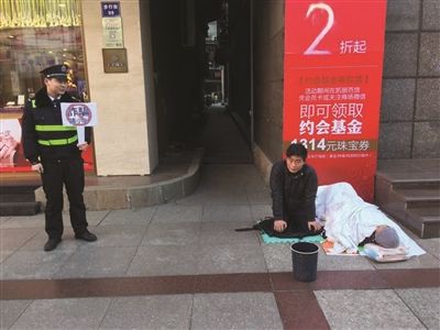 年轻男子跪地乞讨 城管一旁举牌：“诈骗请小心”