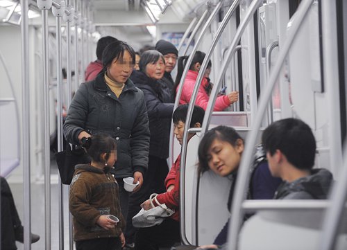 A child and her mother beg in a subway car in Shanghai on February 10, 2011. Photo: IC