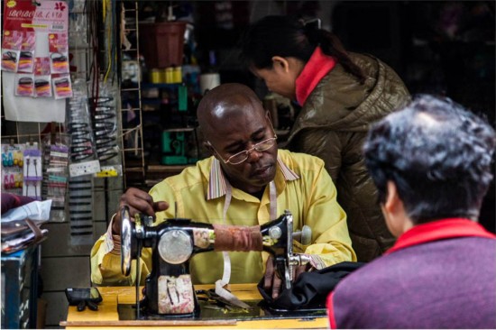 Ted, an Angolan national, does some small business in Guangzhou. He has been in Guangzhou for almost four years and he has good relations with his neighbors. He borrowed the sewing machine from the shop owner for ten yuan each time. [Photo: People's Daily]