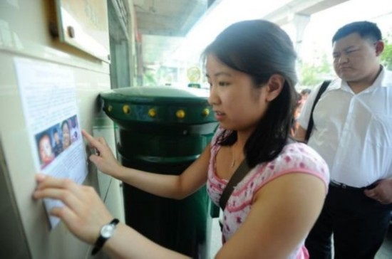 Jenna Cook puts up a poster containing her story, trying to find her birth parents in Wuhan, capital of central China's Hubei Province. [Photo: sina.com.cn]