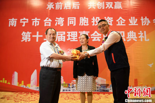 4月27日，廣西南寧市台灣同胞投資企業協會第十二屆理事會在南寧舉行，今年32歲的台商周代祥（右一）正式擔任南寧市台協第十二屆理事會會長，成為目前國內最年輕的地方台協會長。圖為會長印鑒交接儀式。<a target='_blank'  data-cke-saved-href='http://www.chinanews.com/' href='http://www.chinanews.com/'><p  align=