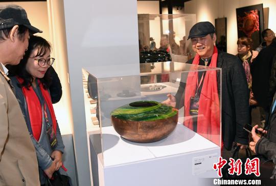 參展藝術家、台灣工藝發展協會常務理事彭坤炎(前右一)介紹其參展作品《春之頌》創作過程。　記者劉可耕 攝