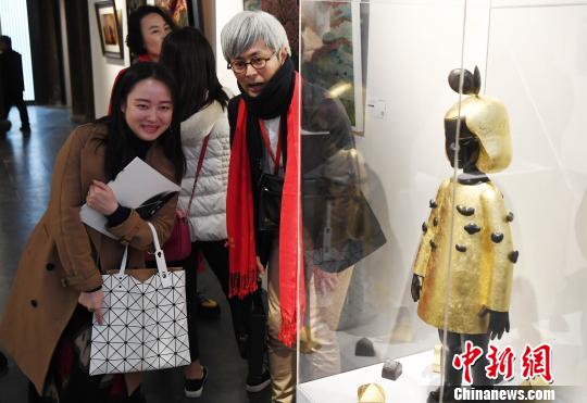 一名女性观众与日本艺术家伊能一三(图中)在其参展作品《和平之车(女孩)》前合影留念。　记者刘可耕 摄