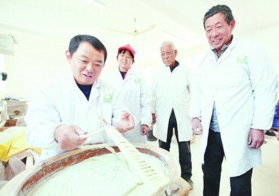 “非遗”传人范红忠（左）与工人们一起切磋技艺