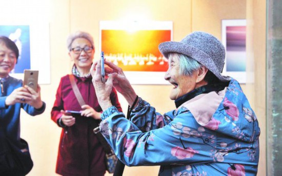 2019年5月8日，《天高任鳥飛》攝影展在安徽畫廊開展，拍攝者是一群平均年齡超過80歲的老人。現場一位愛好攝影的老人用手機拍照。 記者 郭如琦 攝