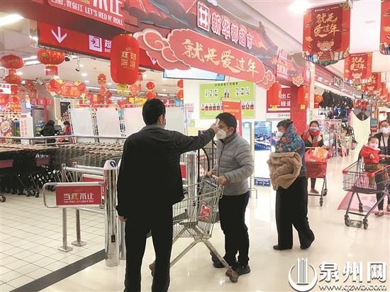 在超市入口，工作人員為顧客測量體溫。 