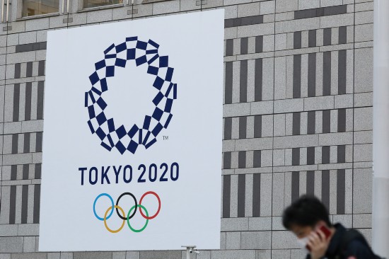 行人經過日本東京都廳前的東京奧運會會徽 （2020年3月25日攝）。