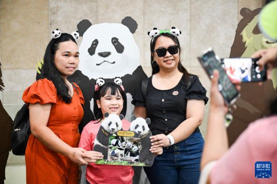 5月17日,在马来西亚吉隆坡的国家动物园,人们在大熊猫馆内举着大熊猫“兴兴”和“靓靓”的牌子合影。新华社记者 程一恒 摄 5月17日,在马来西亚吉隆坡的国家动物园,人们在大熊猫馆内举着大熊猫“兴兴”和“靓靓”的牌子合影。新华社记者 程一恒 摄