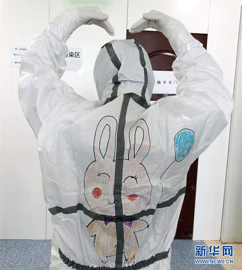 医护人员在武汉儿童医院新冠患儿隔离病房内展示防护服上的卡通画.