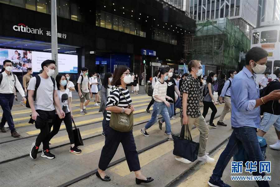 7月27日,在香港中环,行人佩戴口罩走在马路上.