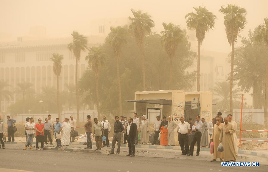 Peoples wait public buses, while a sandstorm hits Kuwait City, capital of Kuwait, Oct. 20, 2014. 