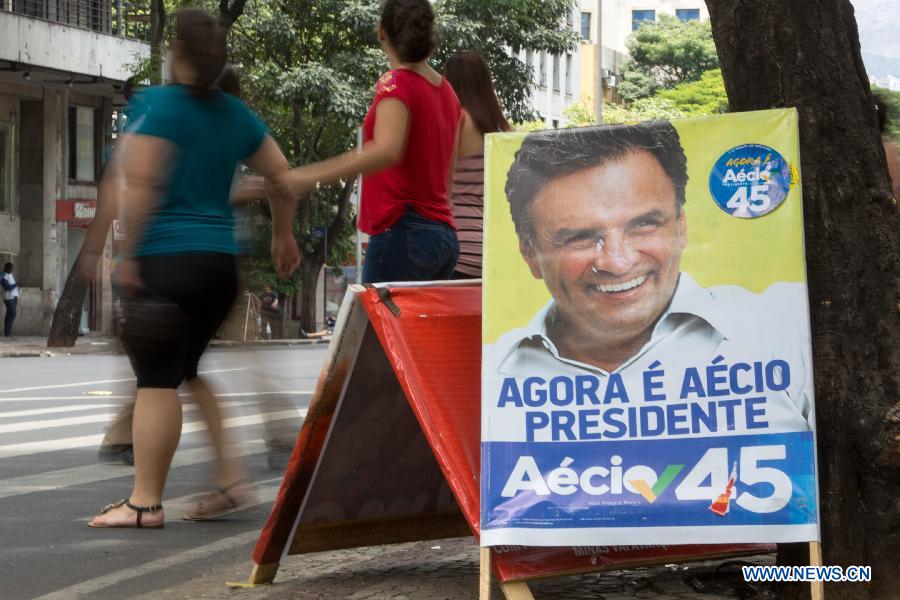 Pedestrains walk past a campaign poster of Brazilian presidential candidate Aecio Neves in Belo Horizonte, Brazil, Oct. 25, 2014. The next Brazilian president will be voted out between Dilma Rousseff of the Workers' Party and Aecio Neves of the Brazilian Social Democratic Party in the presidential runoff scheduled on Oct. 26, 2014. (Xinhua/Xu Zijian) 