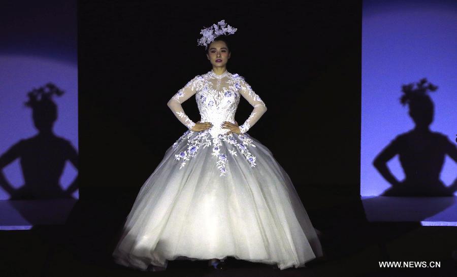 Olympic gymnastics champion Liu Xuan presents a wedding gown designed by Peng Jing during China Fashion Week in Beijing, capital of China, Oct. 26, 2014. 