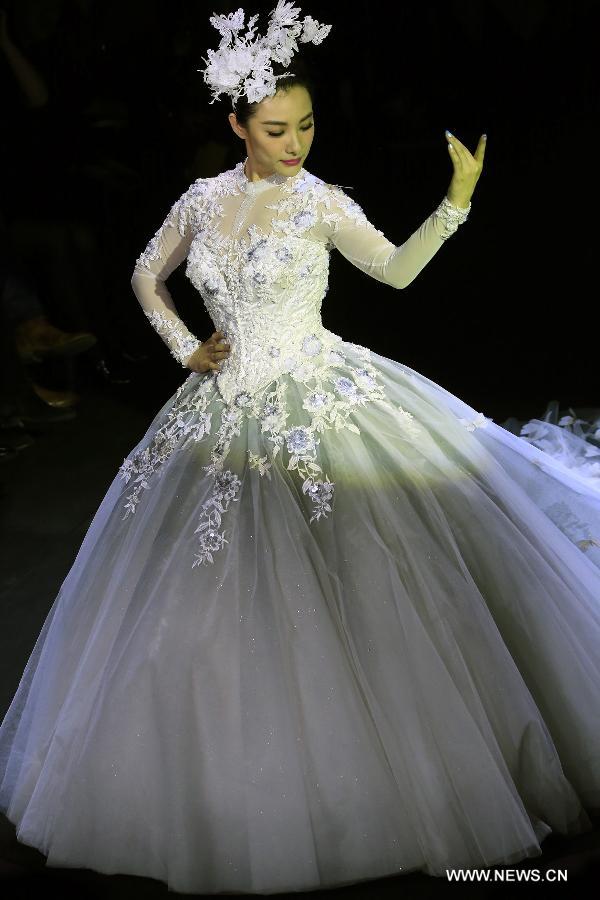 Olympic gymnastics champion Liu Xuan presents a wedding gown designed by Peng Jing during China Fashion Week in Beijing, capital of China, Oct. 26, 2014. 