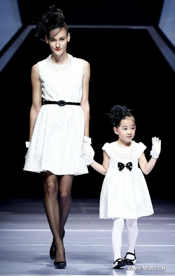 An adult and a child model present creations designed by Dong Wenmei during China Fashion Week in Beijing, capital of China, Oct. 29, 2014. [Xinhua]