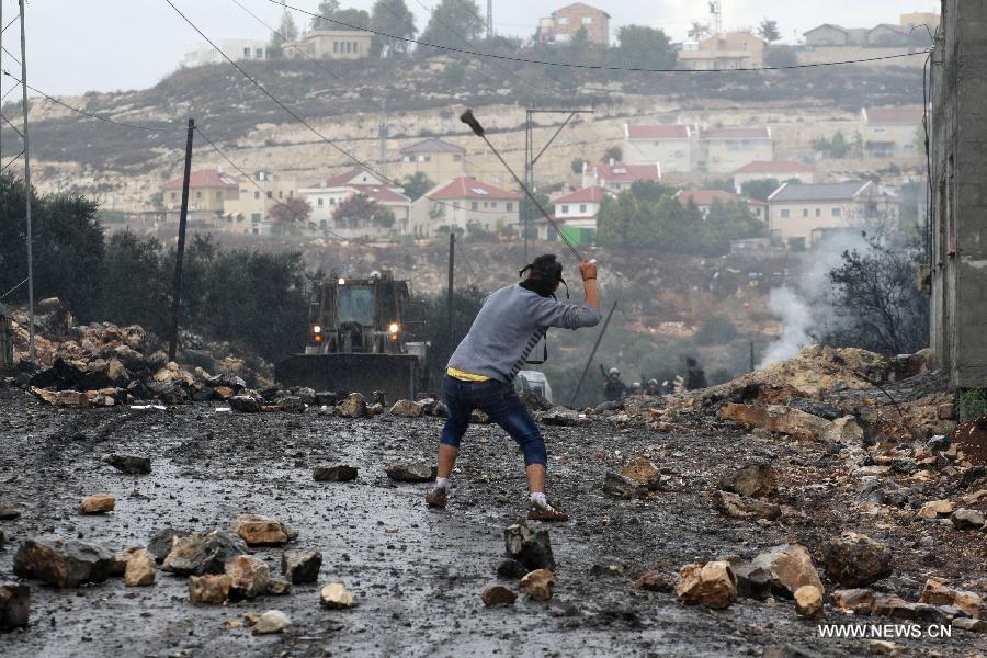 A Palestinian protester throws stones toward Israeli soldiers during a protest in Kufr Qadoom village near the West Bank city of Nablus on Oct. 31, 2014. Clashes broke out Friday between Palestinian protestors and Israeli soldiers in several West Bank towns. (Xinhua/Nidal Eshtayeh) 