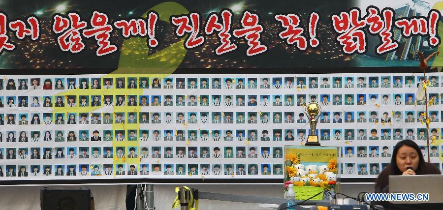 A woman sits in front of a board with photos of the victims of the Sewol ferry disaster in Seoul, South Korea, Nov. 11, 2014.