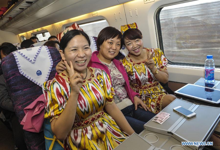 Passengers Sun Zhenzhen (L) from central China's Hubei Province and Liu Xueqin (R) from Urumqi pose for photo on the CRH train D8602 which heads to Hami from Urumqi, capital of northwest China's Xinjiang Uygur Autonomous Region, Nov. 16, 2014.