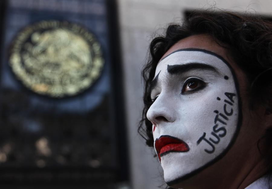 A student wearing white clown makeup with the Spanish word for 'Justice' written on the side of his face, stands outside the Attorney General's office, in Mexico City, Nov. 22, 2014, during a protest demanding the release of students arrested two days earlier, following a massive gathering in the Zocalo. (Xinhua/AP Photo)