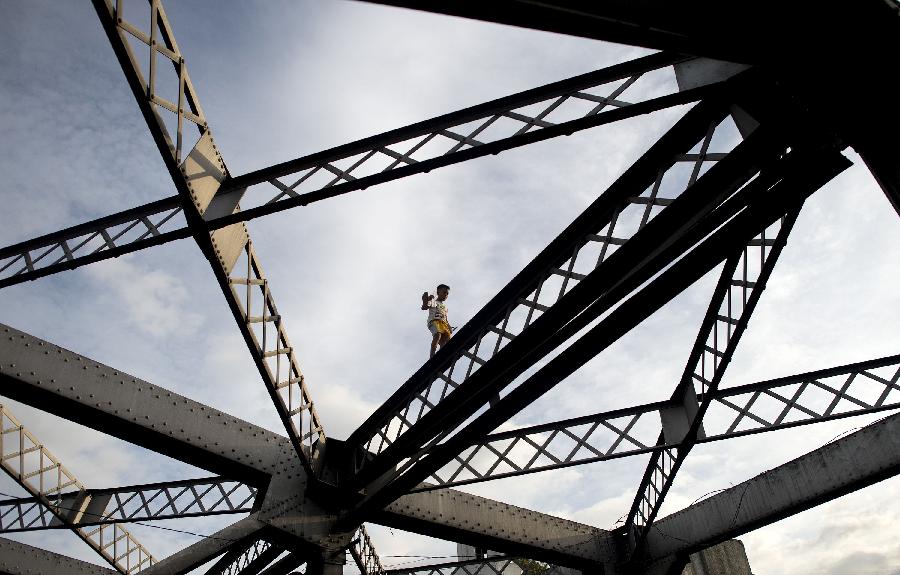 A boy walks on one of the trusses of the Quezon Bridge in Manila, capital of the Philippines, Nov. 20, 2014.  (Xinhua/AFP Photo)