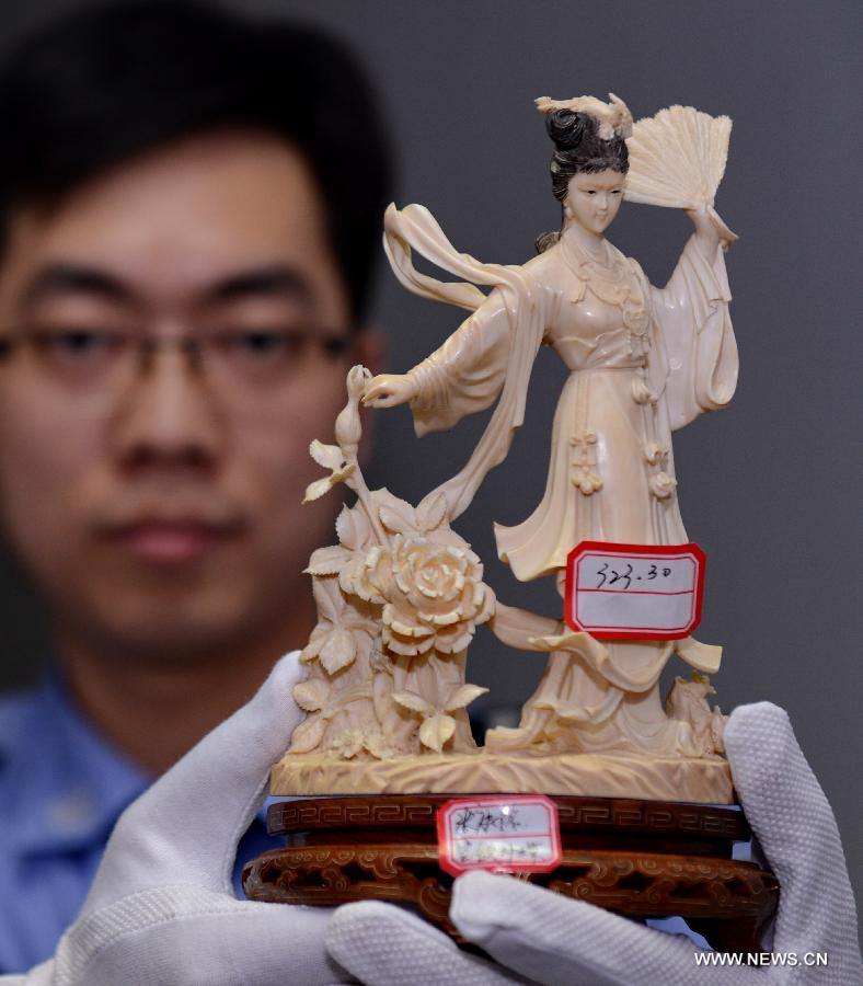 A police officer demonstrates an ivory sculpture seized from a group of wildlife smuggling suspects at the local customs of Fuzhou, capital of southeast China's Fujian Province, Nov. 27, 2014.