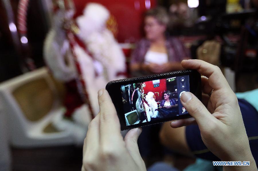 A woman takes a photograph of an actor disguised as Santa Claus in a wagon of the Sao Paulo Metro Yellow Line, in the city of Sao Paulo, Brazil, on Dec. 1, 2014.