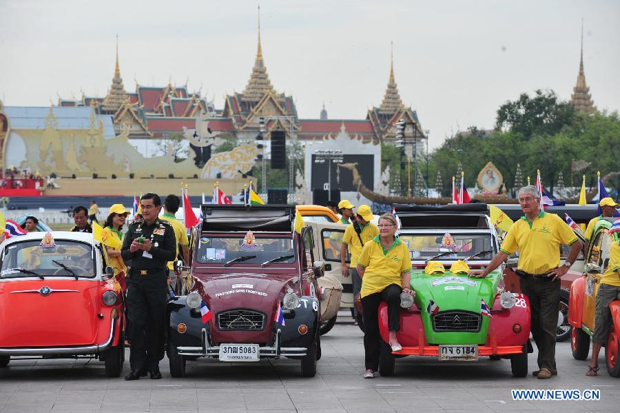 People pose for photos with antique cars during a parade as part of the celebration of Thai King's 87th Birthday Anniversary in front of Grand Palace in Bangkok, Thailand, Dec. 4, 2014.
