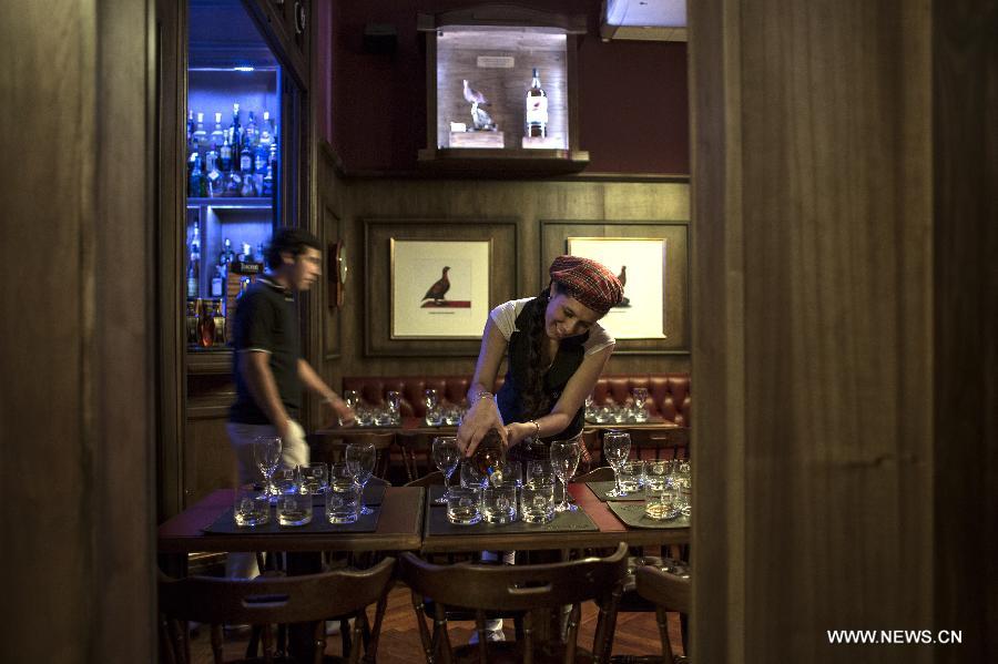 A waitress serves whisky for a catering in the Museum of Whisky in Buenos Aires, capital of Argentina, on Dec. 4, 2014.