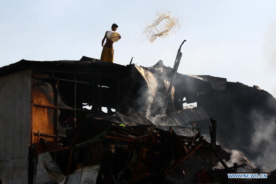 A resident throws a bucket of water to put out a fire that hits a slum area in Manila, the Philippines, Dec. 11, 2014.