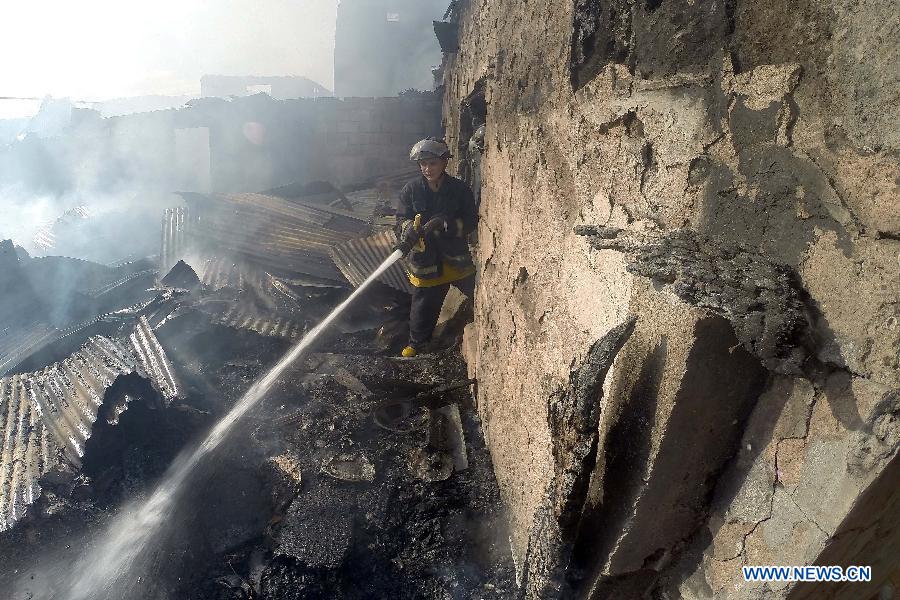 A firefighter puts out a fire that hits a slum area in Manila, the Philippines, Dec. 11, 2014.