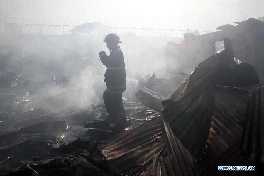 A firefighter walks on burned shanties caused by a fire that hits a slum area in Manila, the Philippines, Dec. 11, 2014.
